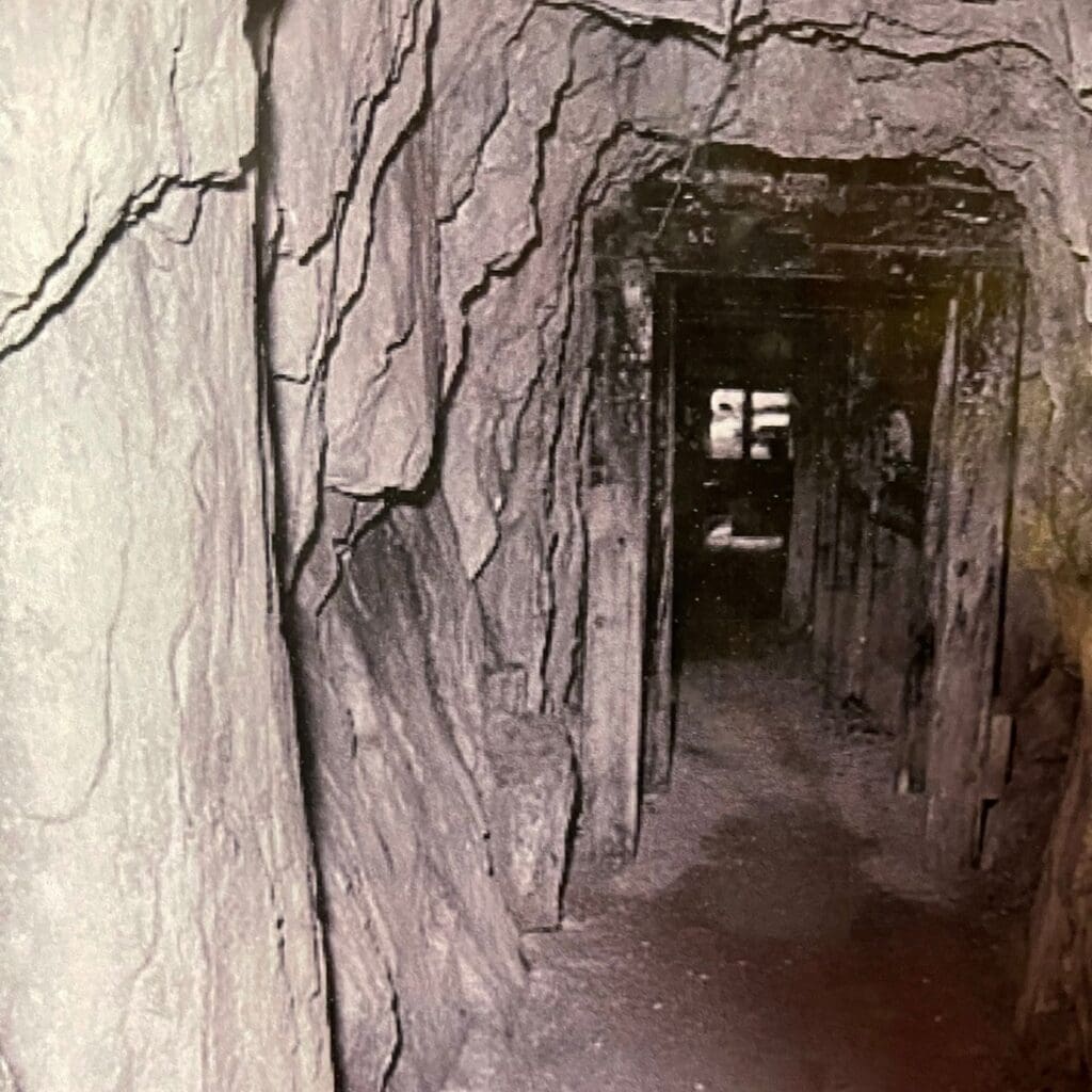 Historical timber-shored tunnel inside the Big Thunder Gold Mine in Keystone, South Dakota, showing original underground mining structures and rock walls