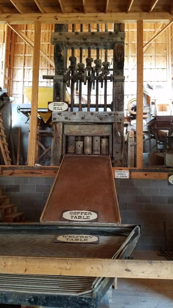 Historic 5-stamp mill, copper table, and Wilfley shaker table ore processing display at Big Thunder Gold Mine museum in Keystone, South Dakota.