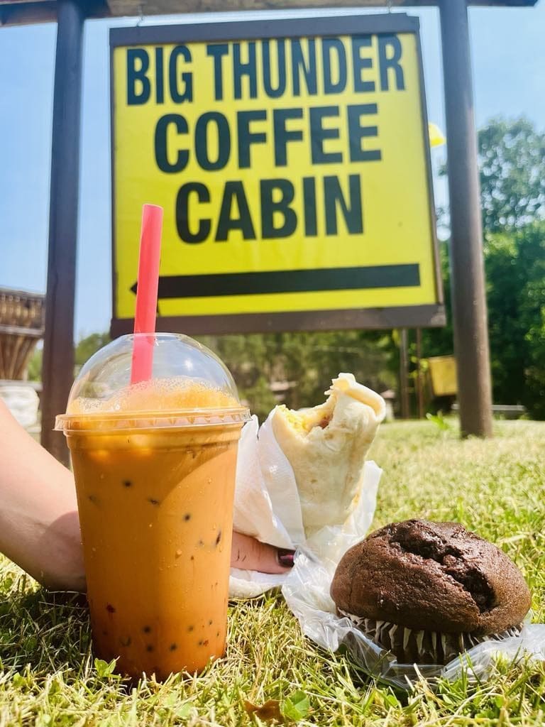Iced coffee, a wrapped breakfast burrito, and a chocolate muffin on green grass in front of the Big Thunder Coffee Cabin at Big Thunder Gold Mine in Keystone, SD