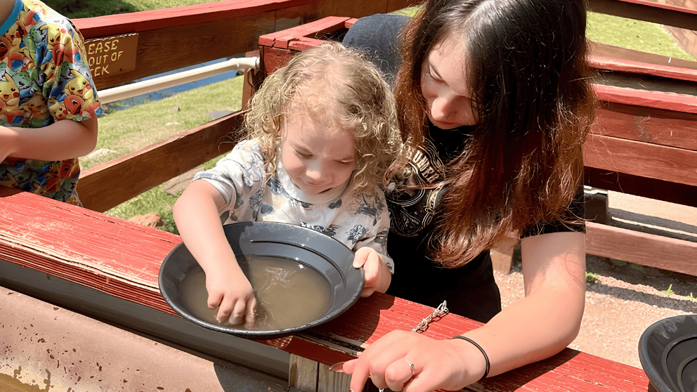 A child and parent learning to pan for gold on-site at Big Thunder Gold Mine in Keystone, SD