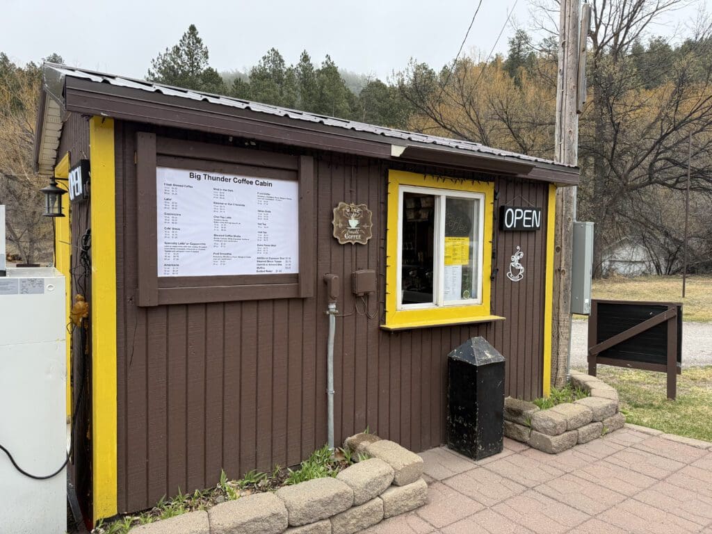 Exterior of the free-standing Big Thunder Coffee Cabin drive-thru coffee shop located in the parking lot of Big Thunder Gold Mine in Keystone, SD.