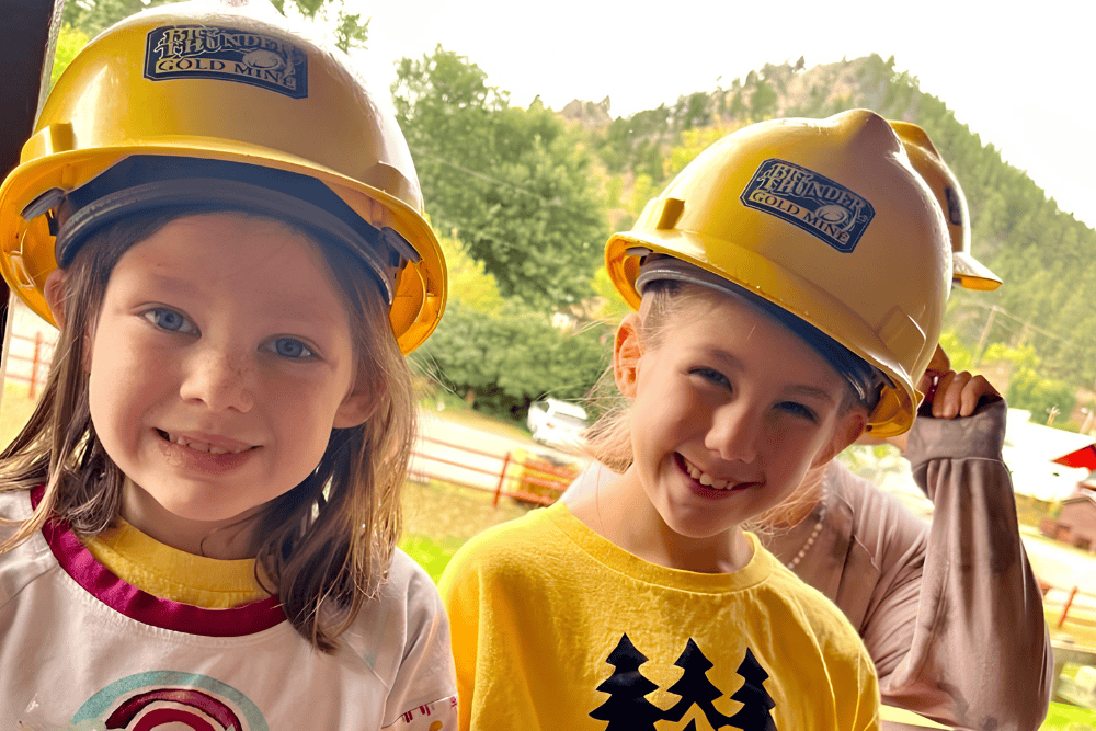 Young smiling kids at Big Thunder Gold Mine wearing yellow mining hats
